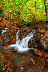 Beautiful autumn landscape with a waterfall in the autumn forest.