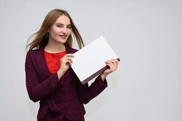 Portrait of a pretty secretary manager brunette girl with long flying hair in a burgundy business suit with a folder on a white background. Smiling, showing emotions.