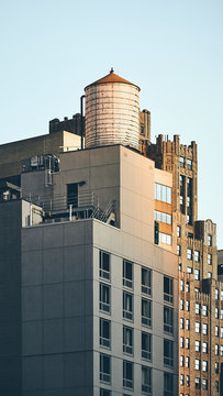 Retro toned picture of a water tower on a rooftop at sunset, New York City, USA.