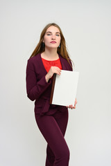 Fototapeta na wymiar Vertical portrait of a pretty secretary manager brunette girl with long flying hair in a burgundy business suit with a folder in her hands on a white background. Smiling, showing emotions.