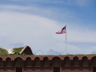 Wide shot of the top portion of Fort Jefferson with a US flag flying from a pole at the Dry Tortugas National Park, Florida.