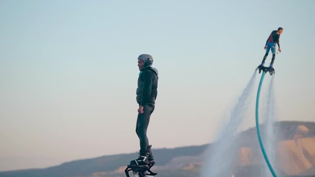 Confident man in black standing on flyboard high in air