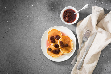 Pancakes with strawberry jam on a white plate. Gray background