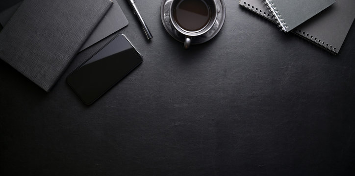 Dark trendy workplace with smartphone and office supplies on black leather table background