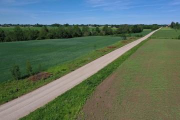Aerial view of gravel road on farmland fields in spring