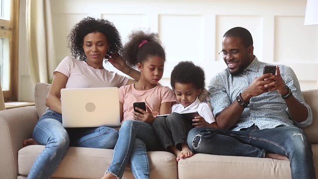 African couple and little kids addicted to modern gadgets