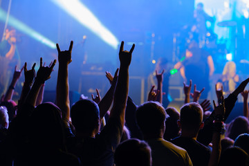 Fans cheering musicians on stage at live rock music concert