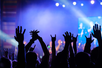 Fans cheering musicians on stage at live rock music concert