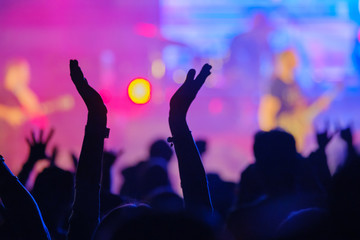 Fans cheering musicians on stage at live rock music concert - obrazy, fototapety, plakaty