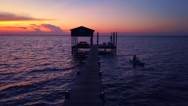 A kayaker sets out from his pier to enjoy the dramatic sunset ovr the water. Spectacular colors