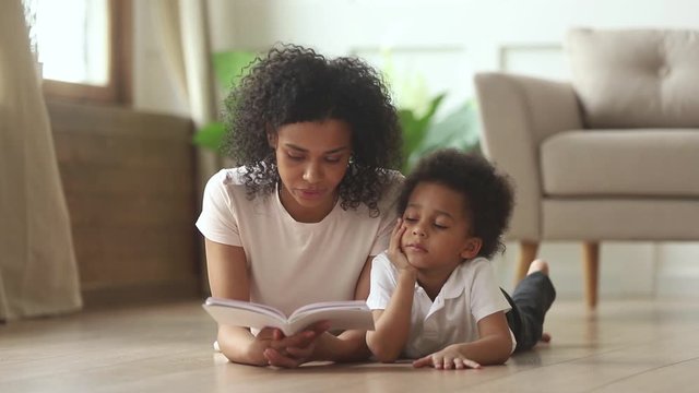 African son lying on floor with mother reading fairytale story