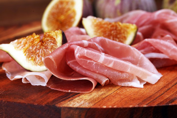 Italian prosciutto crudo or jamon with sliced figs Raw ham.