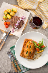 lunch set Puff pastry bun with spinach and grilled beef steak and glass of red wine on the table