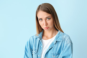 Offended young woman on color background