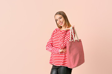 Beautiful young woman with bag on color background