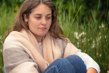 Emotion concept. A young unhappy woman sitting in a park. Burnout and depression.