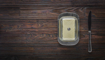 butter in butter dish on wooden background. top view