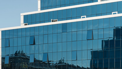 reflection of neighbourhood in glass facade of a modern building