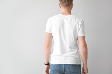 Man in stylish t-shirt on light background, back view