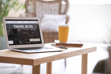Laptop with open page of travel blog on table