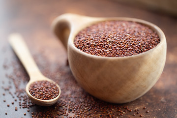 Red quinoa grains. Seeds of red quinoa - Chenopodium quinoa, in wooden cup and spoon  