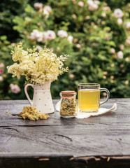Fresh Meadowsweet, Filipendula ulmaria flowers in jug shape vase and it`s herbal tea in glass, tea...