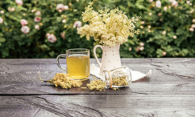 Fresh Meadowsweet, Filipendula ulmaria flowers in jug shape vase and it`s herbal tea in glass, tea...