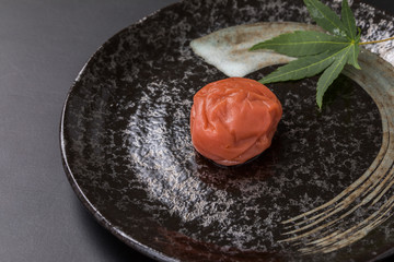 黒背景に高級感のある黒いお皿に箸と梅干しと紅葉コピースペース