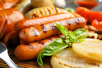 Tasty grilled sausages on wooden board, closeup