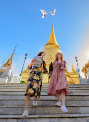 young tourist women walking through the palace temple in Bangkok of Thailand, Emerald Buddha Temple, Wat Phra Kaew, Bangkok Royal Palace popular tourist place - obrazy, fototapety, plakaty