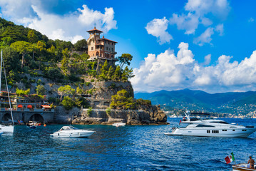Portofino, Italy - AUGUST 15, 2019: Portofino harbor, yachts and water boats, cliff building / popular European resort / Italian Riviera