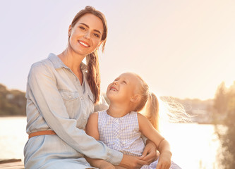 Happy mother and her little daughter near river