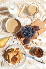 Appetizing toasts with chocolate paste, coffee with milk, figs and blueberries on the table.