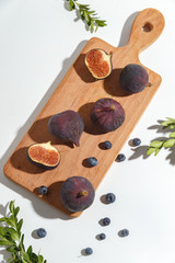 Figs, pear and blueberries on a cutting wooden board.