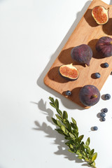 Figs, pear and blueberries on a cutting wooden board.