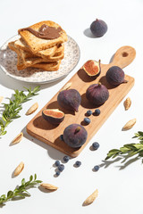 Figs, pear and blueberries and toasts with chocolate on a cutting wooden board.
