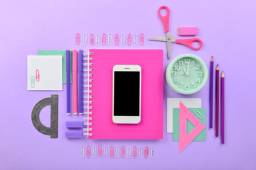 Mobile phone and stationery on color background