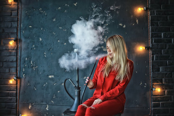 girl smokes  hookah / beautiful glamorous girl in red dress smokes a hookah, the sexy model in a night club smokes