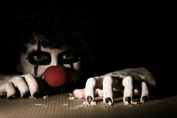 A terrible creepy clown peeps out of the basement and scratches the floor with his claws.