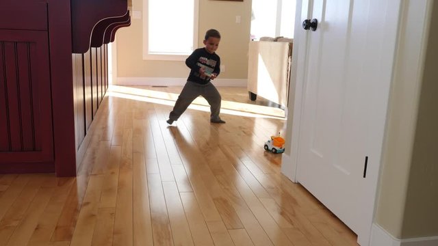 A cute little boy plays with his toy remote control car in his house