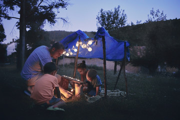 Father with children playing under their backyard tent.