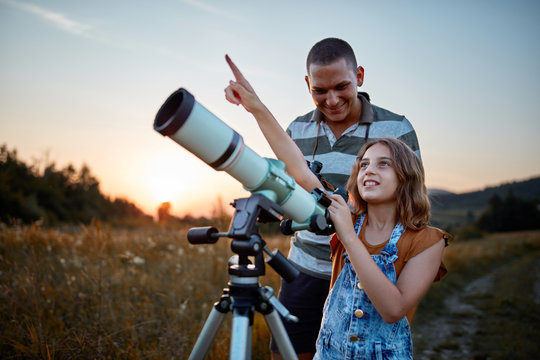 Father and daughter observing the sky with a telescope.