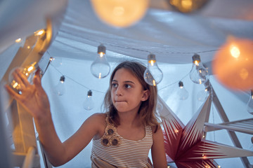 Little girl playing and making a house tent in the room.