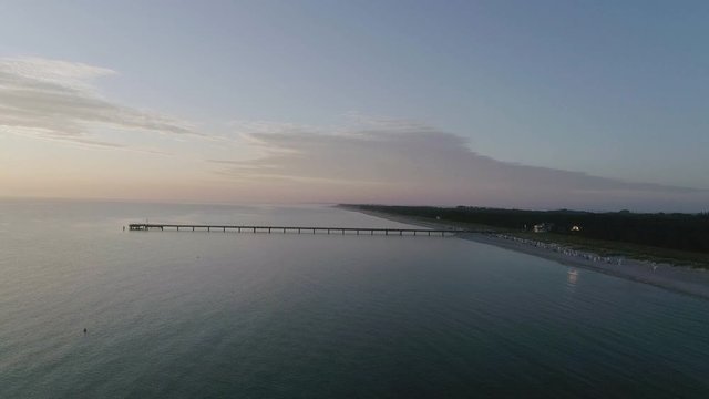 Distant Pier Stretching out into Sea at Sunset
