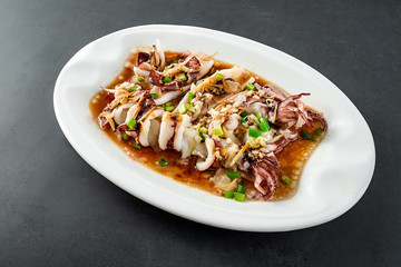 Chinese Chaoshan home cooking, a plate of oyster sauce steamed small squid on a black background