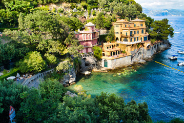 Fototapeta na wymiar Portofino, Italy - AUGUST 15, 2019: Beautiful harbor in the Italian Riviera, hotels on the cliff, boats on the water / a popular resort in Europe
