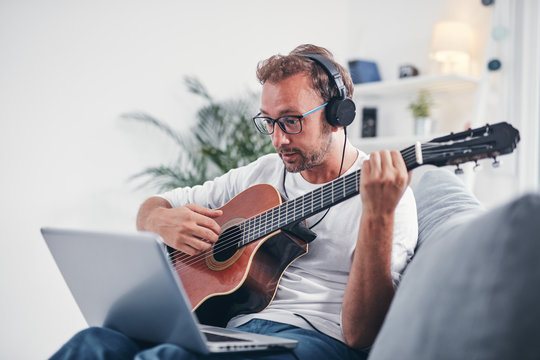 Man playing acoustic guitar in the living room.