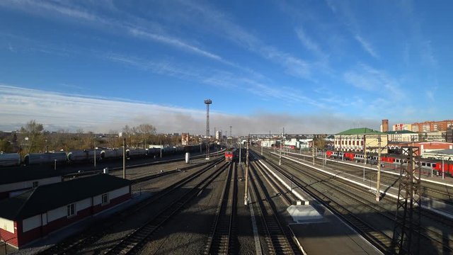 View of the railway station from a height of a pedestrian crossing over the railway tracks. Sunny day. The train arrives.