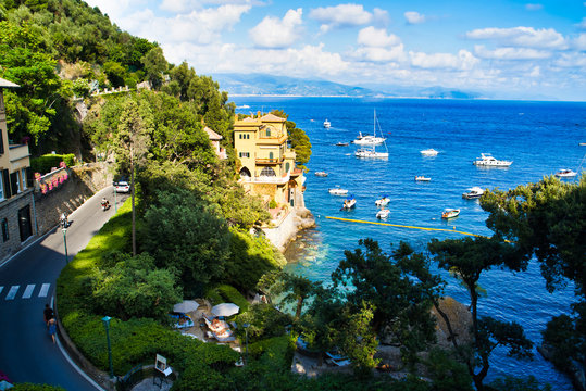 Portofino, Italy - AUGUST 15, 2019: The road along the beautiful coast of the Italian Riviera / houses on the rocks / boats and yachts in the bay / popular European resort