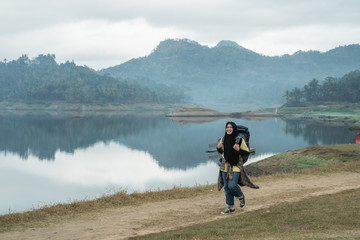 Muslim woman tourist with backpack in the side lake